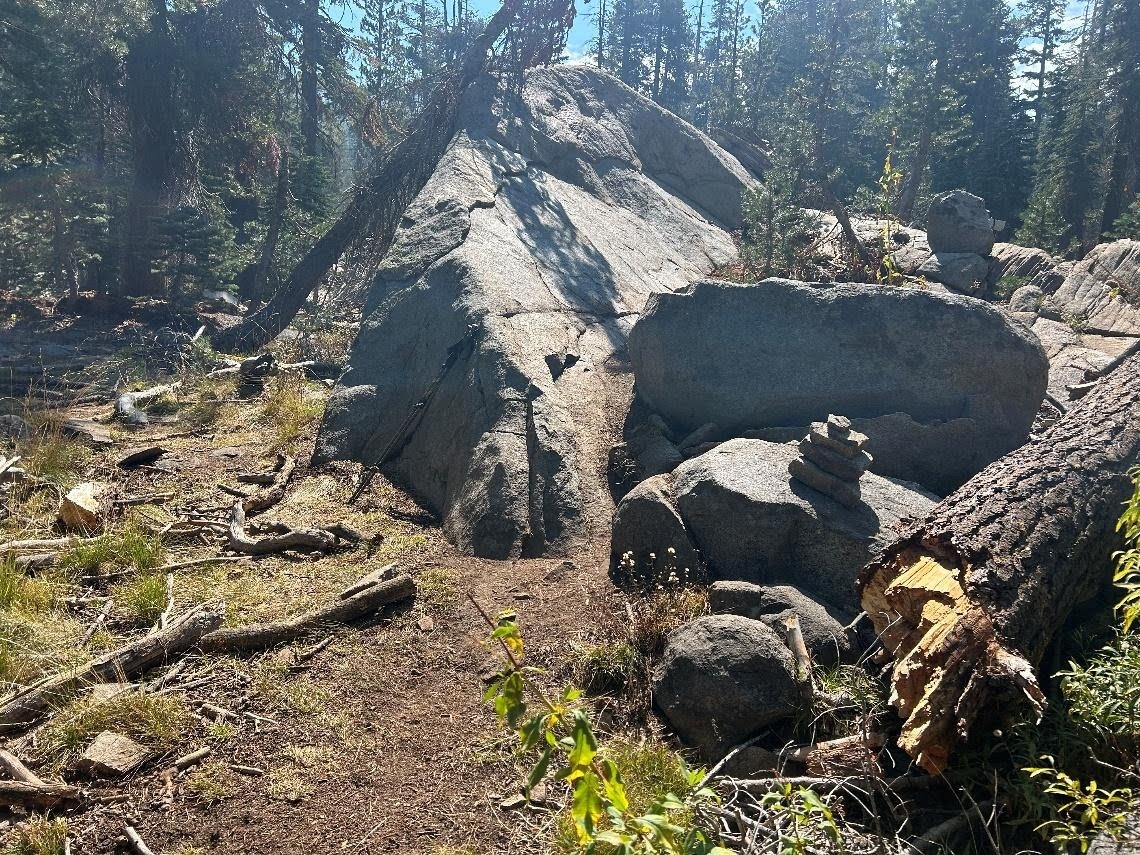Large granite boulders blocking the trail with a small stack of rocks marking the route over the top