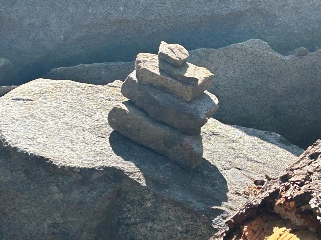 Close-up of a cairn of stacked rocks on a granite slab marking the trail