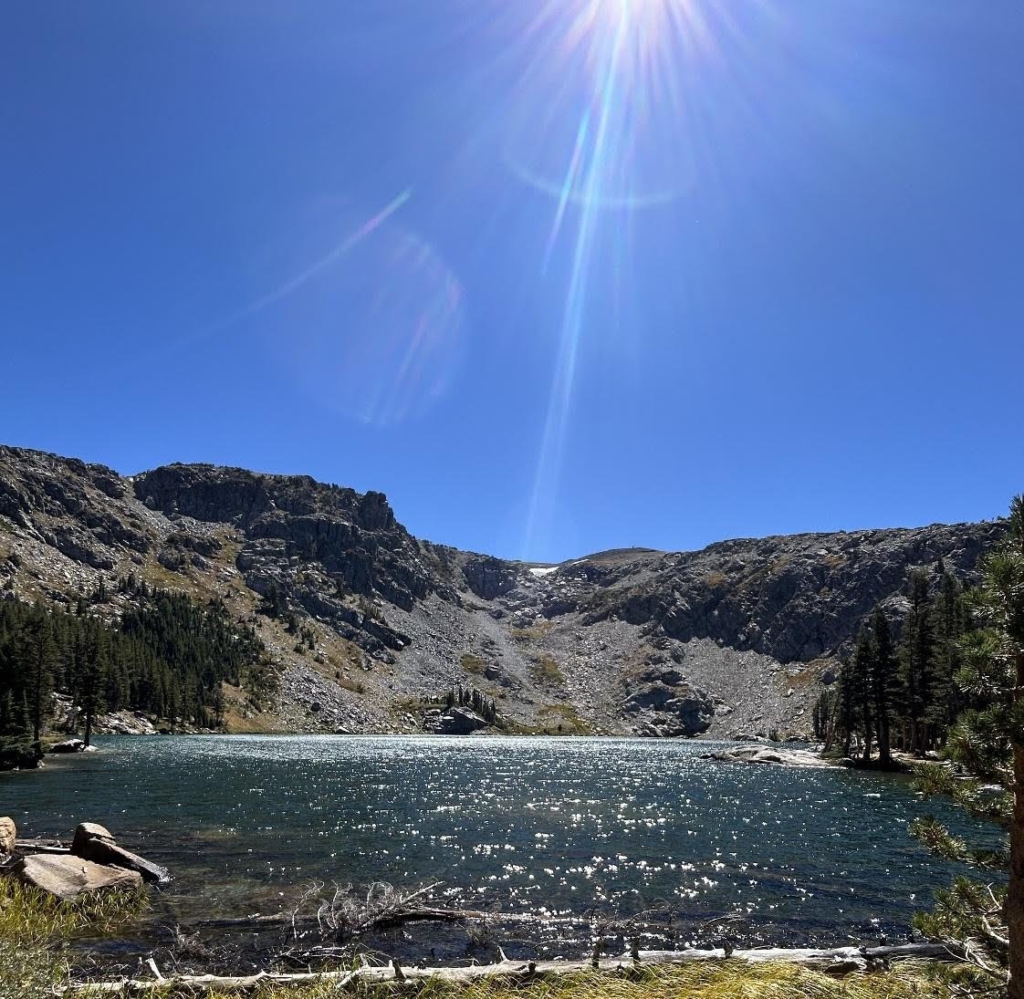 Emigrant Lake sparkling under bright sun beneath a rocky granite ridge in the Tahoe region